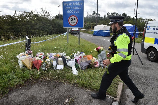 A police officer lays a floral tribute at the scene 