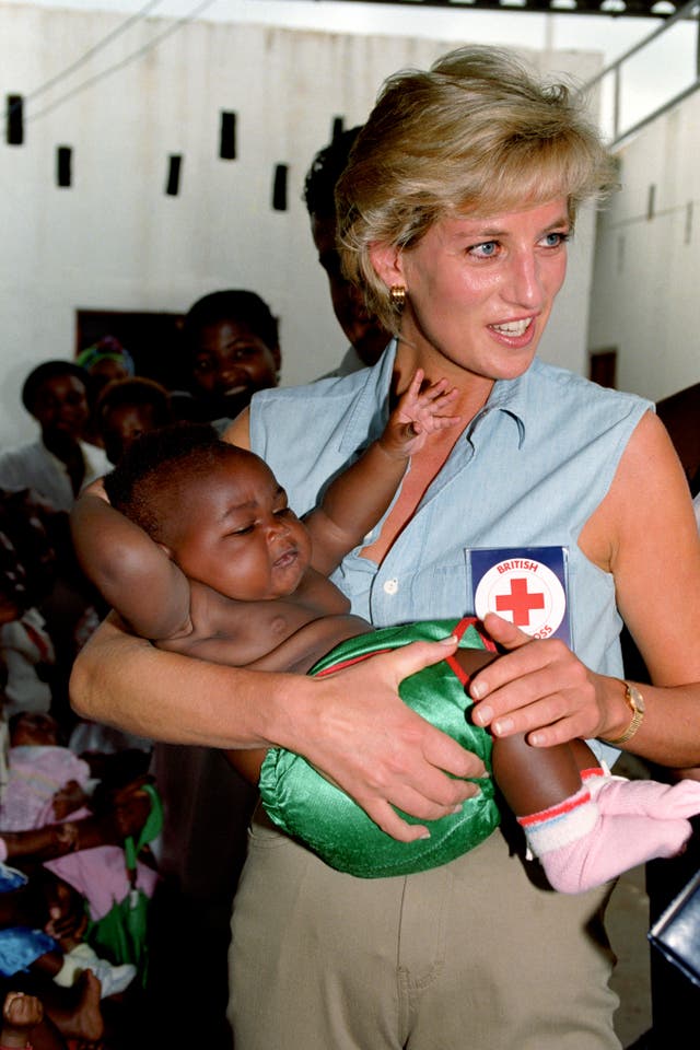 Diana, Princess of Wales - in her denim top - cuddling a baby at the Kikolo health post in Angola (John Stillwell/PA)