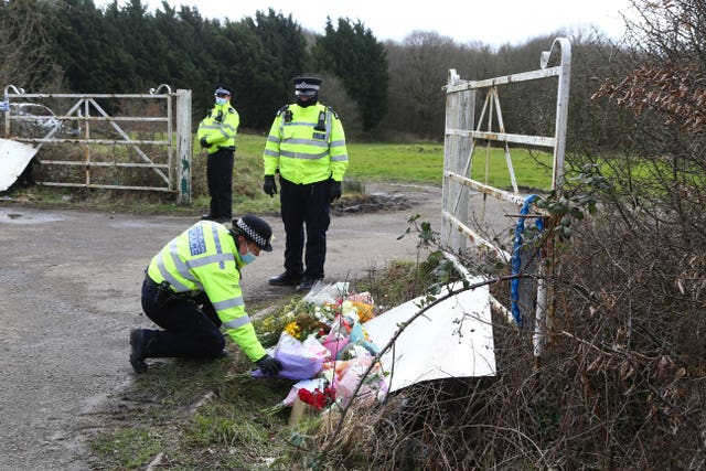 A police officer places flowers left by members of the public at the site as Metropolitan Police continue their search near Great Chart, Kent