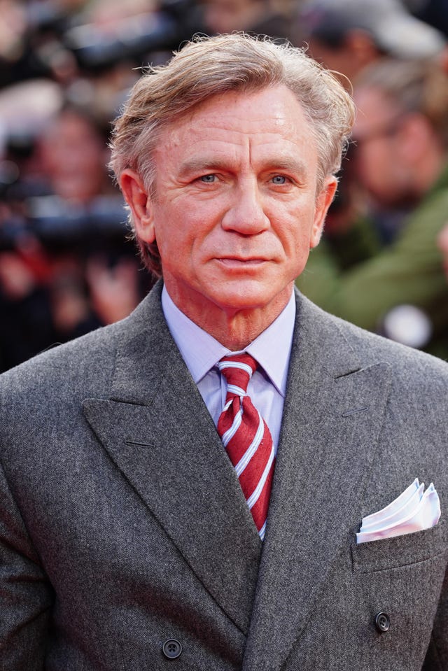 Daniel Craig wearing a grey suit with a red and white tie