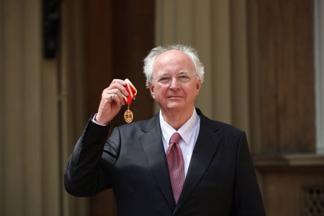 Sir Philip Pullman holding his medal after being knighted at Buckingham Palace