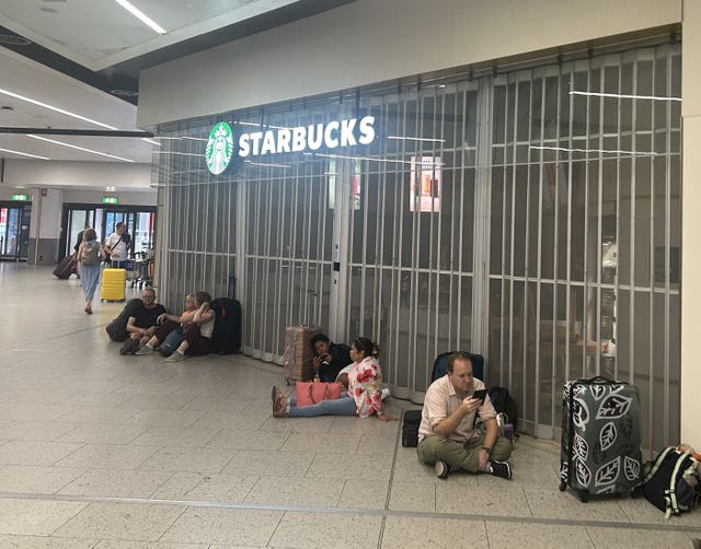 People sit outside the closed Starbucks at Gatwick airport