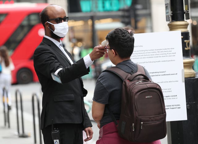 Customers have their temperature checked by staff before entering the Apple store