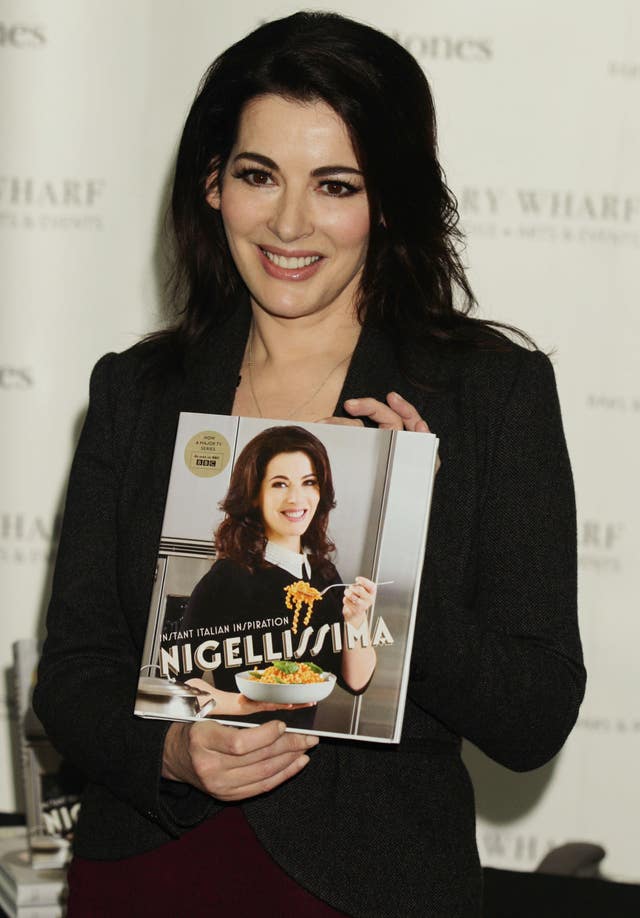 Nigella Lawson holding a copy of her book, Nigellissima