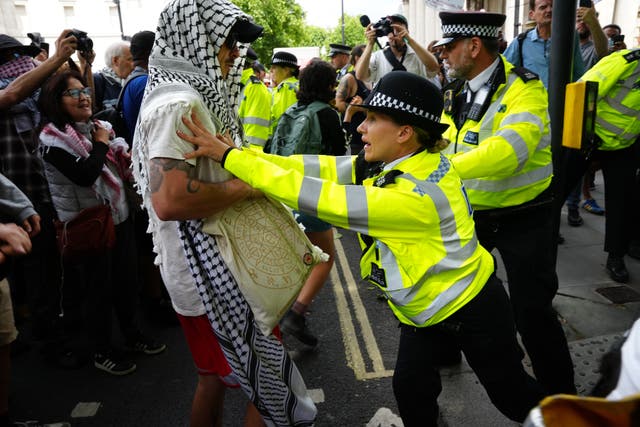 Police officers and protesters during a demonstration in support of Palestine Action at Trafalgar Square