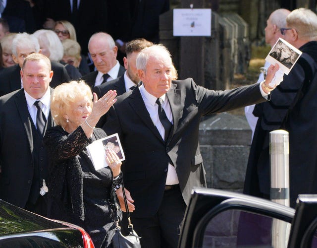 Robert Sullivan waves to the waiting crowd as he leaves the funeral