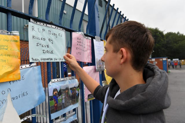 Messages from supporters are placed on a fence outside Gigg Lane 