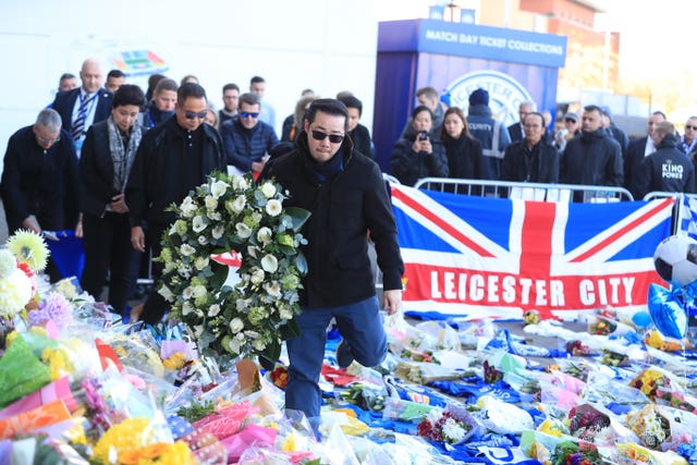 Aiyawatt Srivaddhanaprabha (front) and family members walk through tributes