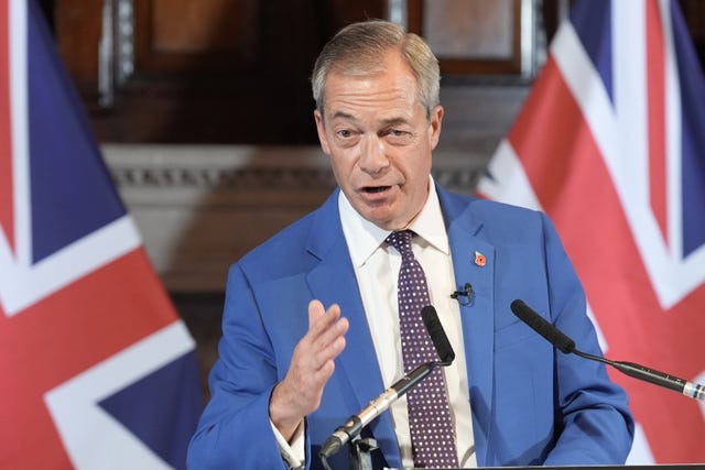 Nigel Farage speaking from a lectern, with British flags behind him