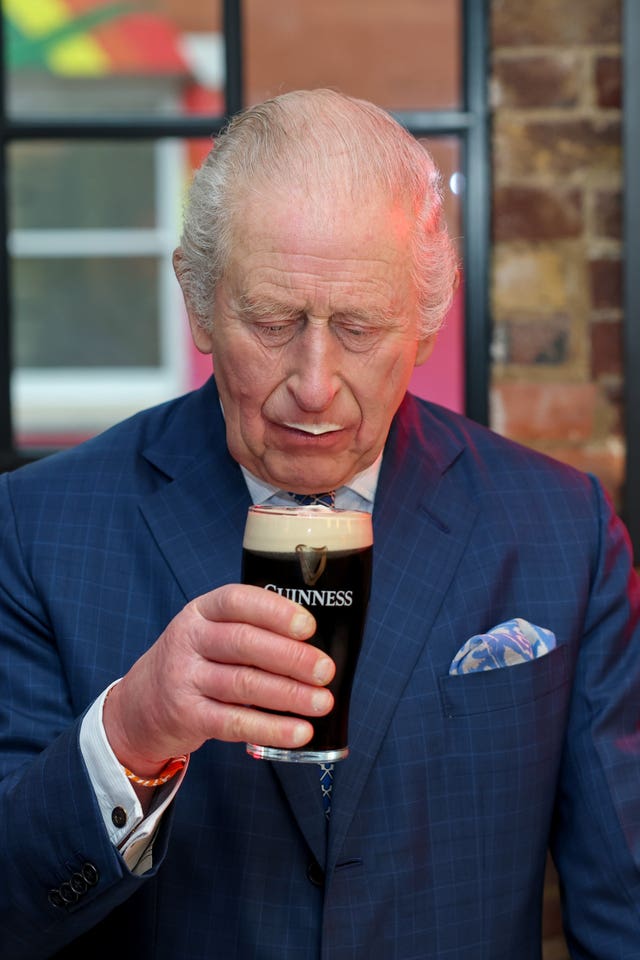 The King with some foam from the head of a pint of Guinness after taking a sip