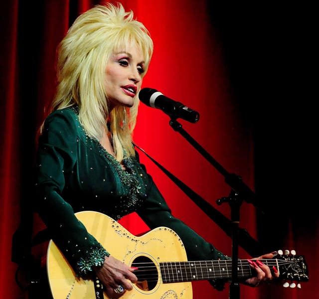 Dolly Parton playing a guitar while performing