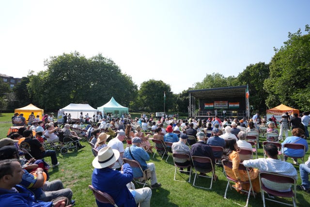 People watching performances on a stage in a park