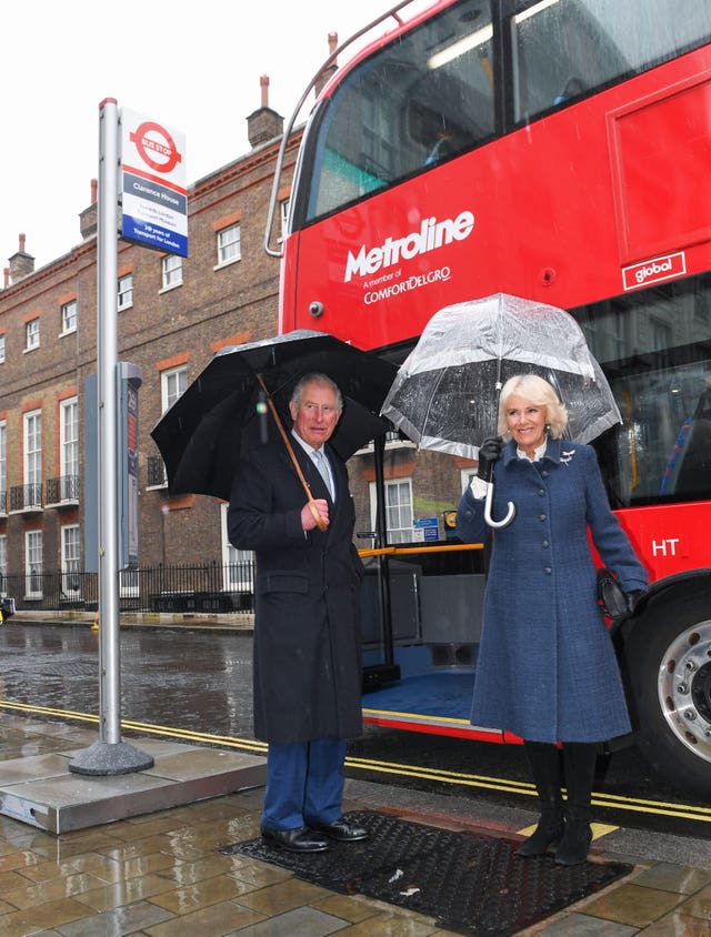 The Prince of Wales and Duchess of Cornwall prepare to board a new electric double decker bus at Clarence House in London to travel to the London Transport Museum