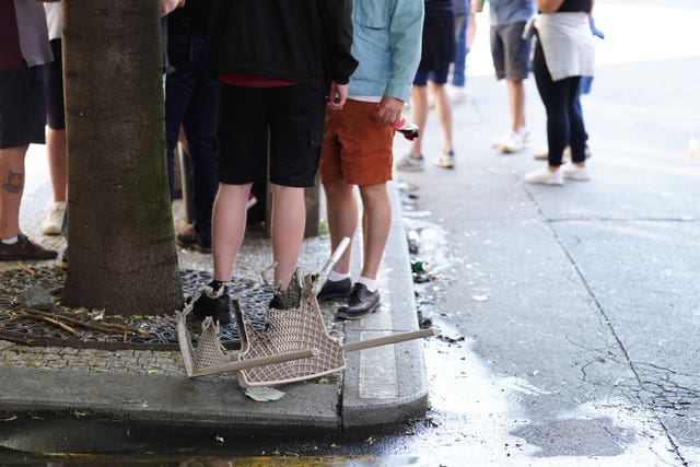 People stand near a chair which was set alight, following a clash between West Ham and Fiorentina fans in Prague ahead of the the Uefa Europa Conference League Final at the Fortuna Arena