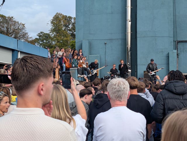U2 performing to students from their old school