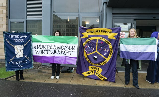 Sandie Peggie supporters standing outside, holding flags and placards
