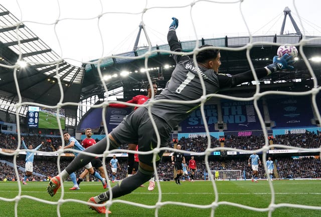 Manchester City's Phil Foden, background left, heads past diving Manchester United keeper Altay Bayindir