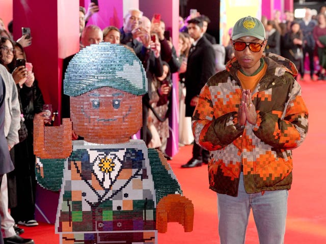 Pharrell Williams stands next to a cut-out Lego figure