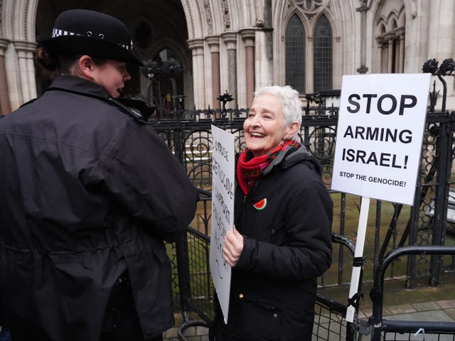 A police officer speaking to a protester holding a placard outside the High Court