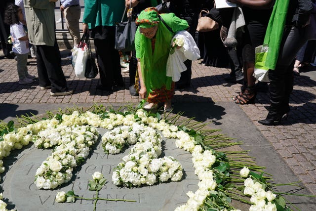 People place white roses in memory of the 72 victims