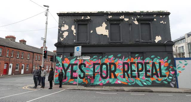 People stand beside a mural in Dun Laoghaire calling for a repeal of the Eighth Amendment of the Irish Constitution (Niall Carson/PA)