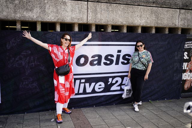 Oasis fans pose for pictures outside the Principality Stadium, Cardiff, as the band’s long-awaited reunion tour kicks off in Wales