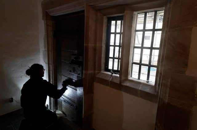 A door is worked on by a restorer on Holy Island (Owen Humphreys/PA)