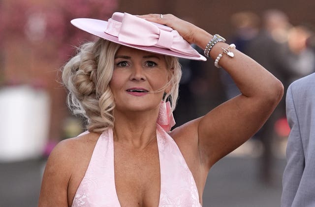 A racegoer holds on to her hat