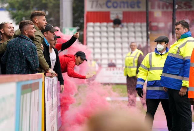 Swindon fans are spoken to by stewards as they throw objects towards the pitch