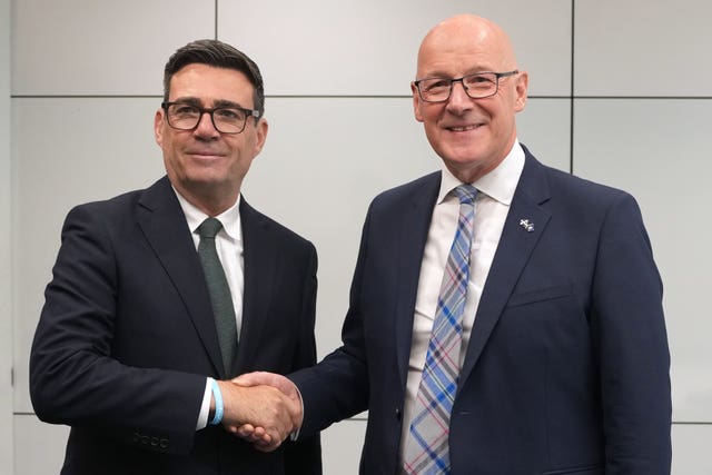 Andy Burnham and John Swinney standing side by side and shaking hands