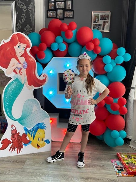 Olivia Pratt Korbel standing in front of a blue and red balloon wall