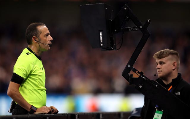 Referee Cuneyt Cakir checks the pitch side camera to check a VAR decision