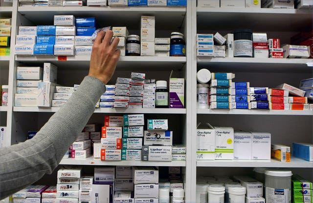 A pharmacist reaching for medicine from a shelf