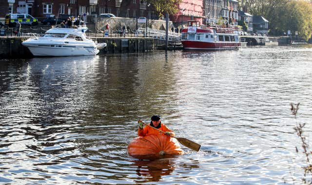 Tom Pearcy rowing a pumpkin boat down the River Ouse
