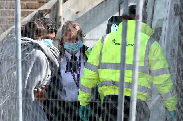 A woman and child, thought to be migrants, are escorted to a van by Border Force officials