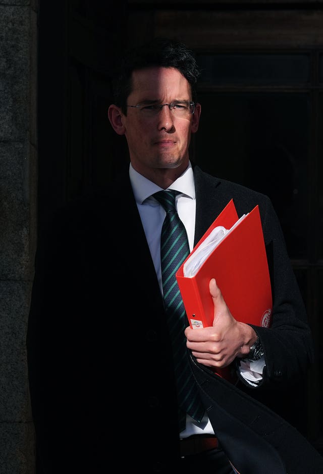 Enoch Burke leaving a building, holding a red folder