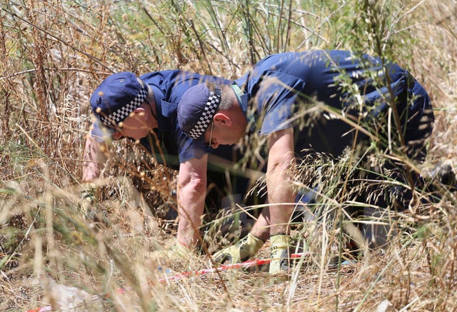 British police conduct a finger-tip search in 2014 of an area of scrubland close to where Madeleine McCann went missing