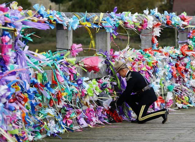 A member of the Legion of Frontiersmen lays a wreath amongst the tributes