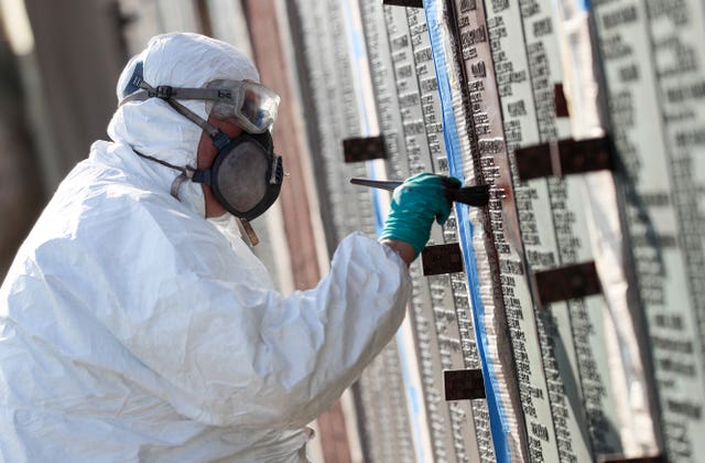 Workers from the Commonwealth War Graves Commission apply a bronzing solution to the names on one of the panels