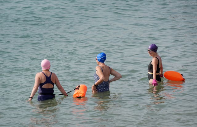 Swimmers head into the sea during the morning sunshine on the beach in Dover, Kent