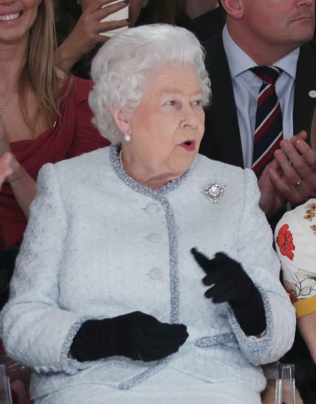 The Queen reacts to one of the outfits during Richard Quinn's runway show (Yui Mok/PA)