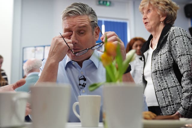 Sir Keir Starmer holding his glasses in his left hand as he wipes his eye with his other