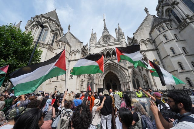 Palestine Action protesters waving flags outside the Royal Courts of Justice