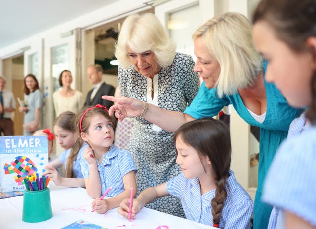 A teacher speaks to Camilla as children listen