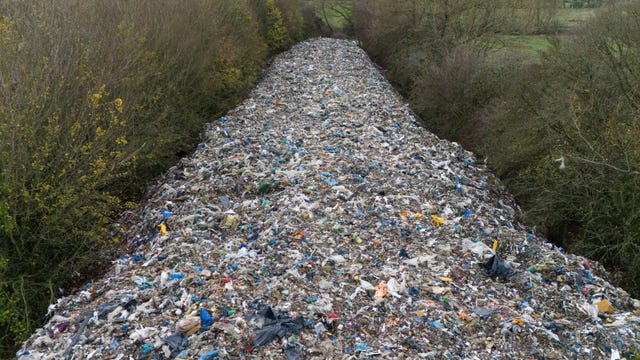 The pile of waste stretching away into the distance between two lines of trees