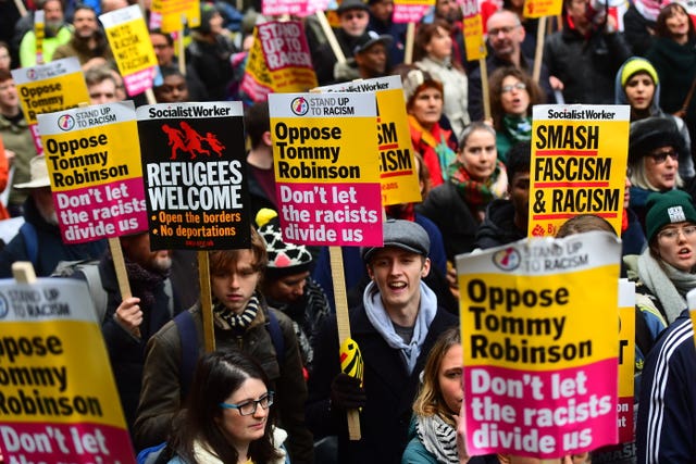 People hold placards opposing Tommy Robinson