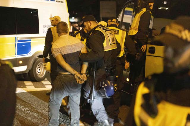 A man in handcuffs is led away by police