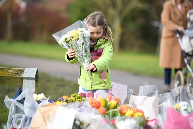 Noelle Simmons, 4, leaves a floral tribute outside the home of Captain Sir Tom Moore in Marston Moretaine, Bedfordshire
