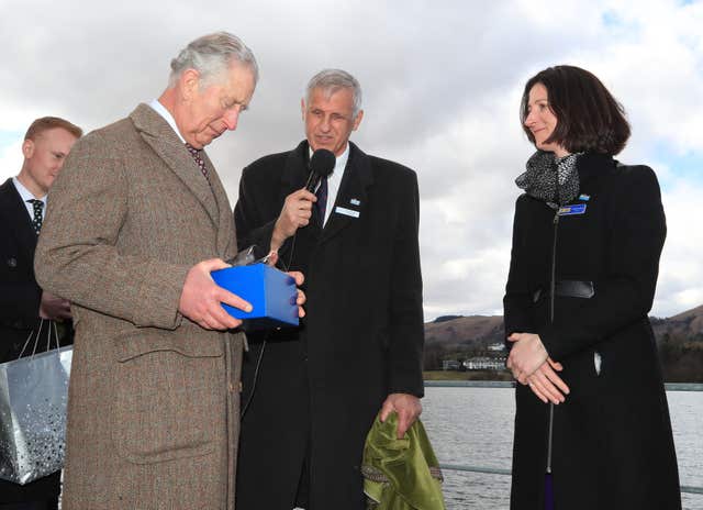 Charles is presented with a Cumbrian crystal tumbler by non-executive directorLucinda Langton of Ullswater Steamers company in Glenridding, Cumbria (Peter Byrne/PA)