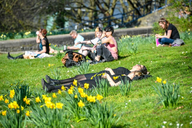 People relax in bright sunshine among blooming daffodils at Castle Park, Bristol (Ben Birchall/PA)